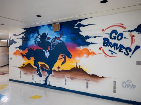 A colorful mural shows a person riding a horse along a hallway wall and the words Go Braves.