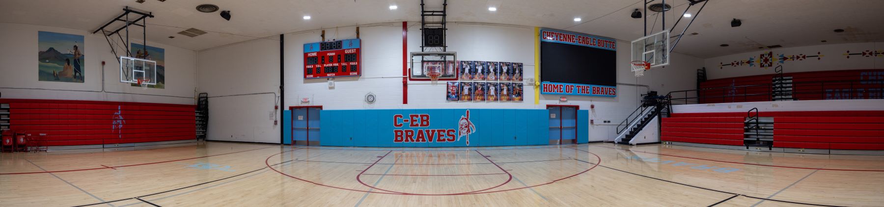 A basketball court featuring team posters and CEB-Braves sign in the school gym.
