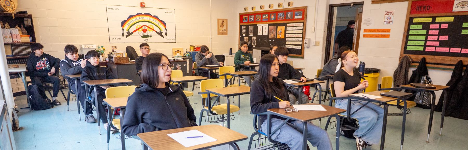 Students attentively sitting at their desks in a lively classroom, focused on their lessons and interacting with each other.