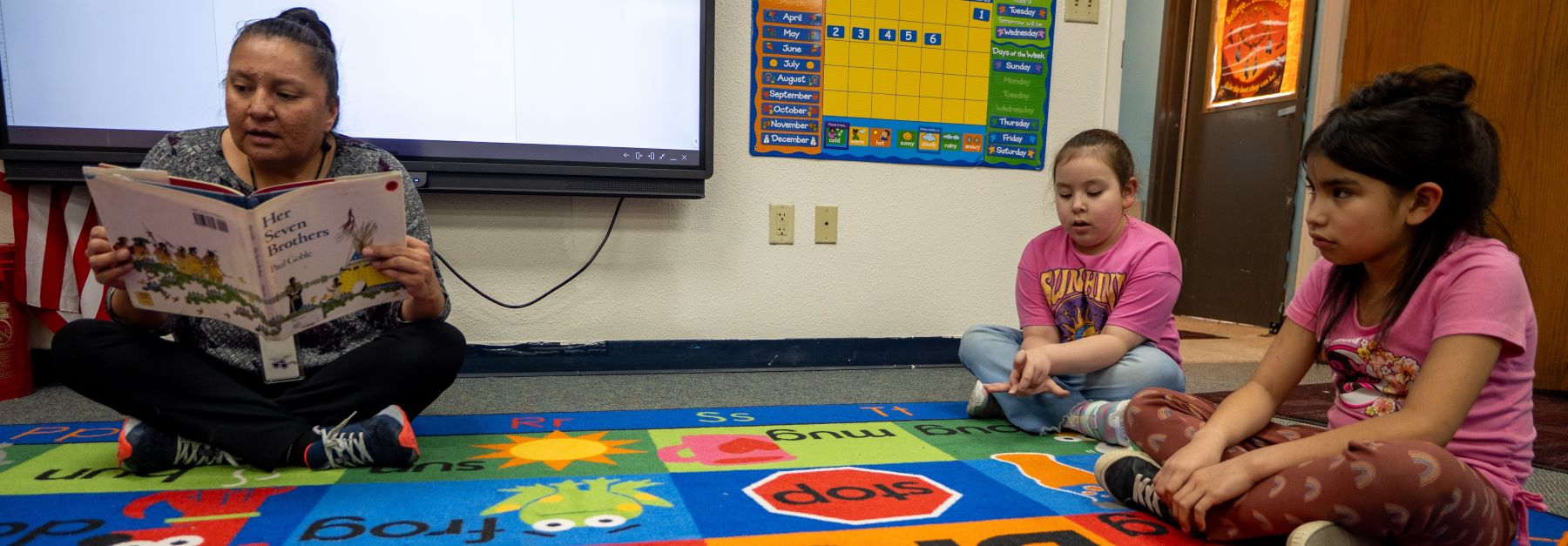 Teacher reading book to students in class.