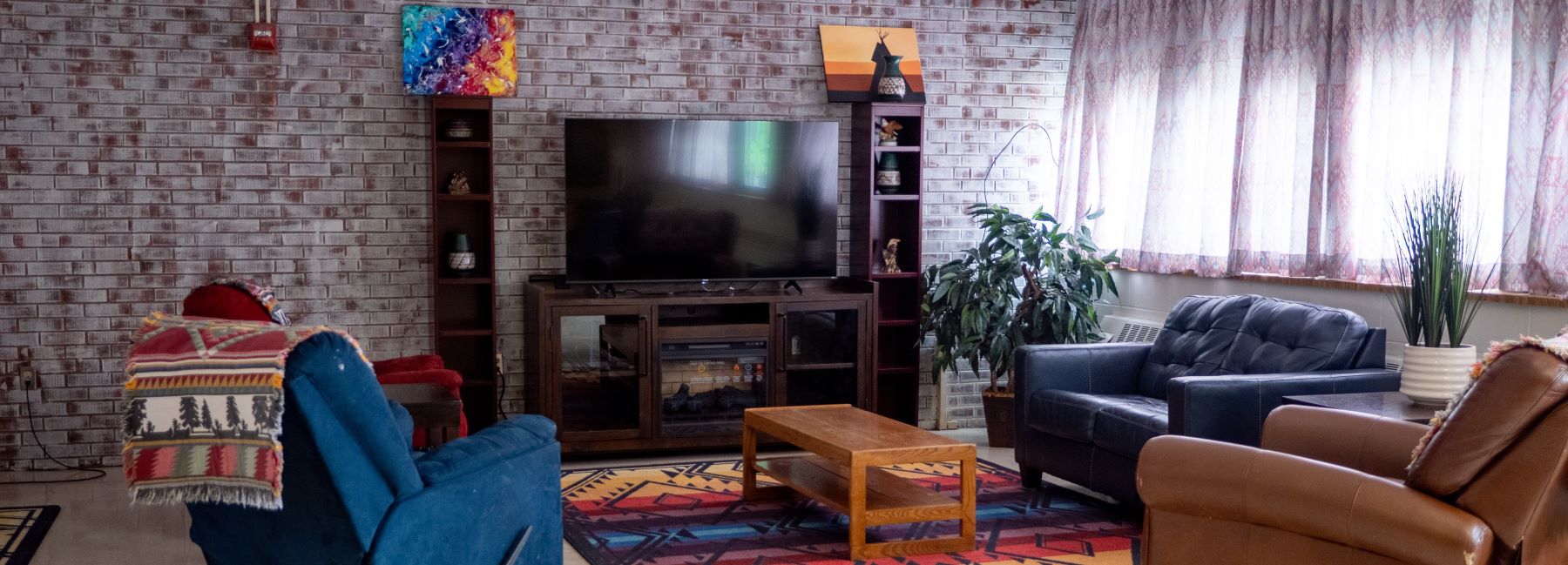 A cozy school student lounge featuring a television, comfortable chairs, and a colorful rug on the floor.