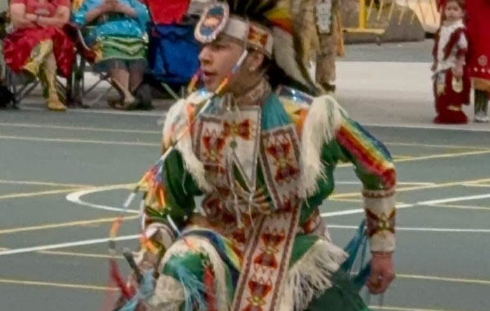Student dressed in regalia and dancing in the center of the gym