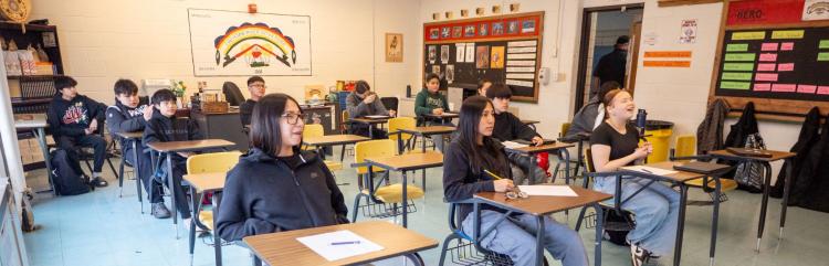 Students attentively sitting at their desks in a lively classroom, focused on their lessons and interacting with each other.