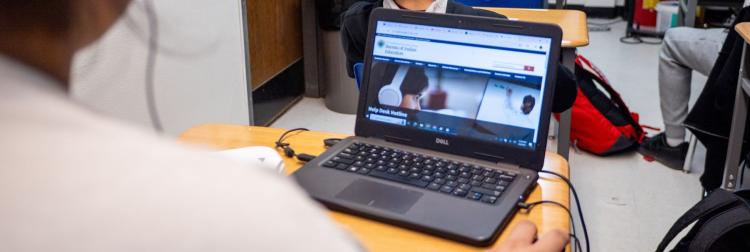 A student working at a desk with a school laptop, engaged in their studies.