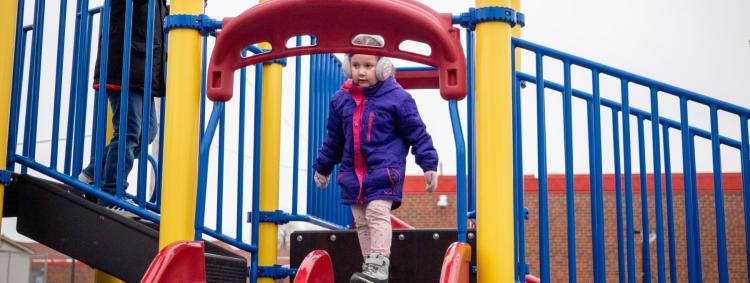 A young student enjoying a fun ride down a bright slide at a playground.